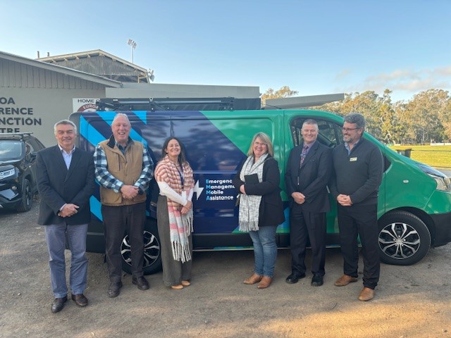 A group of six people standing outside in front of a van