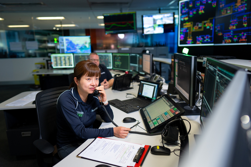 A woman working at a computer desk while speaking on the phone