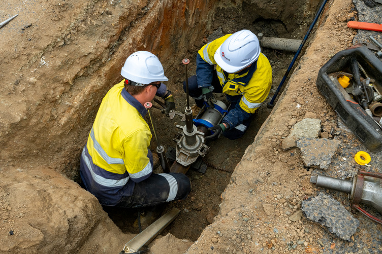 Two people working on a gas pipe underground