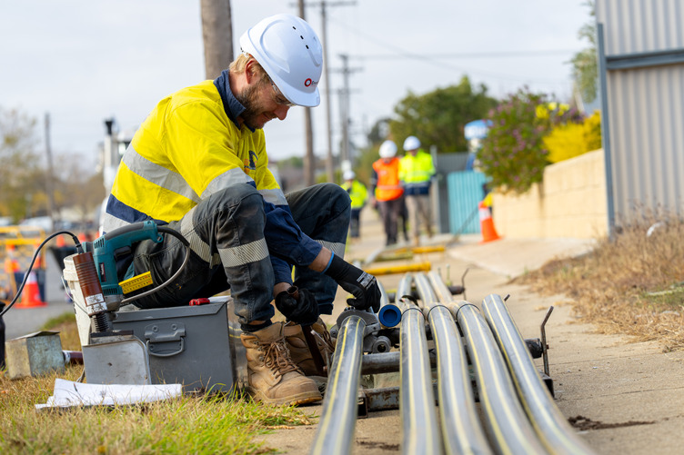 A man in high vis working on a gas line on a street