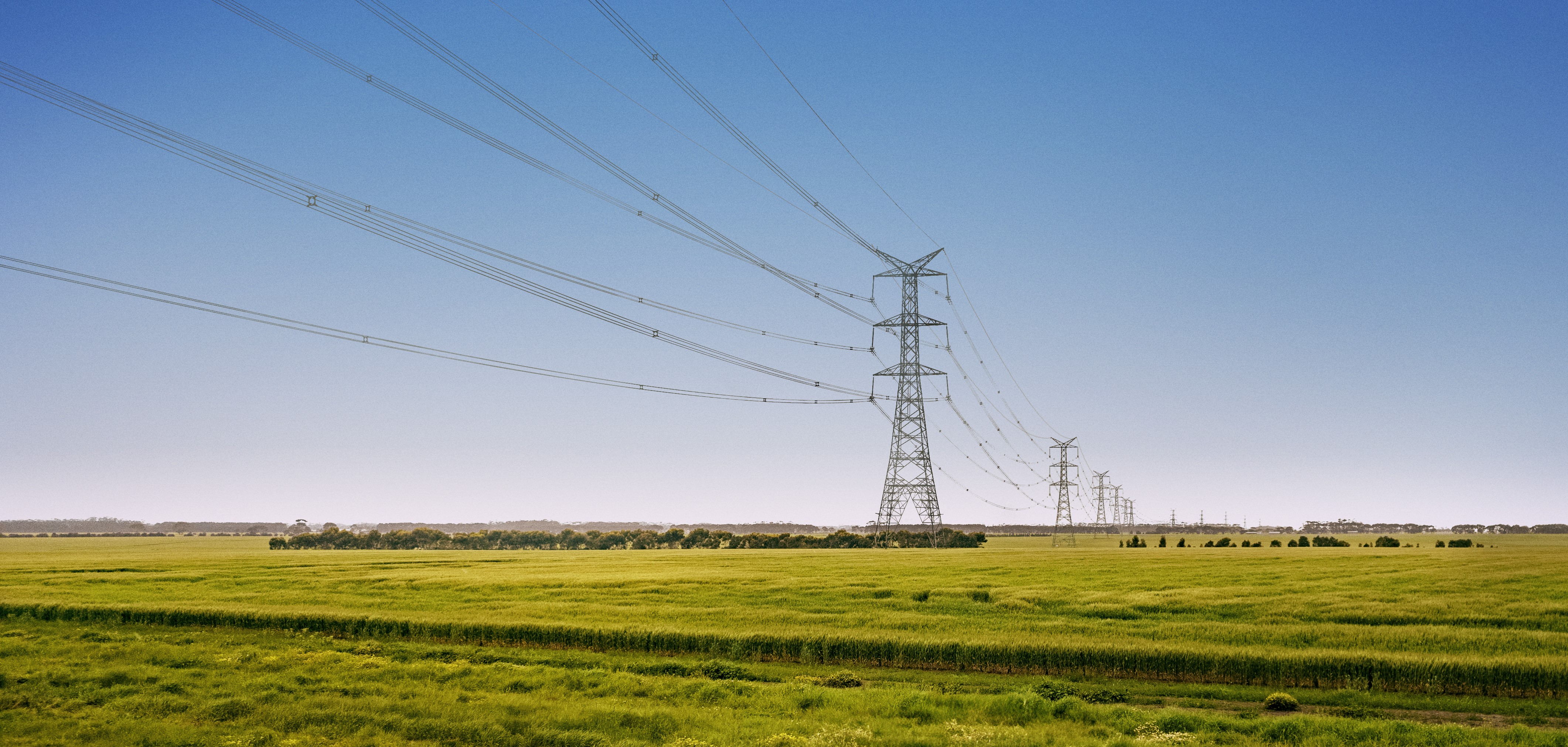 Transmission towers spanning across a grassy field
