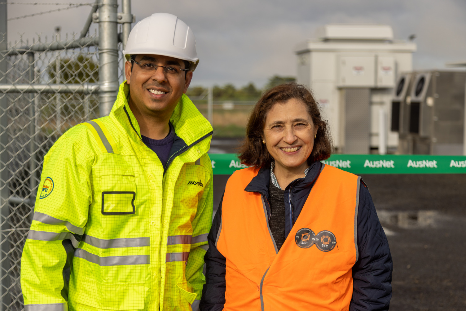 A man and woman in work uniform outside