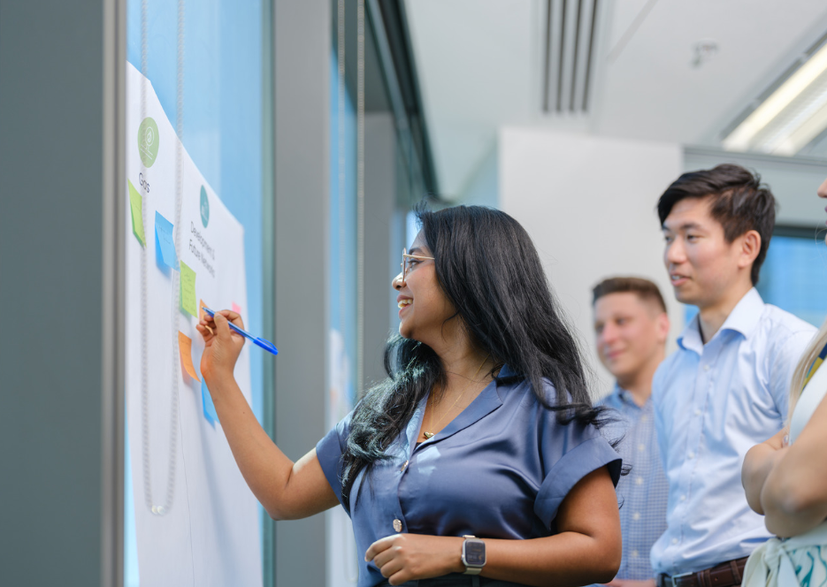 A group of people watching a woman draw on notes