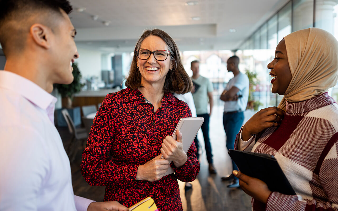 Three people smiling and talking in an office