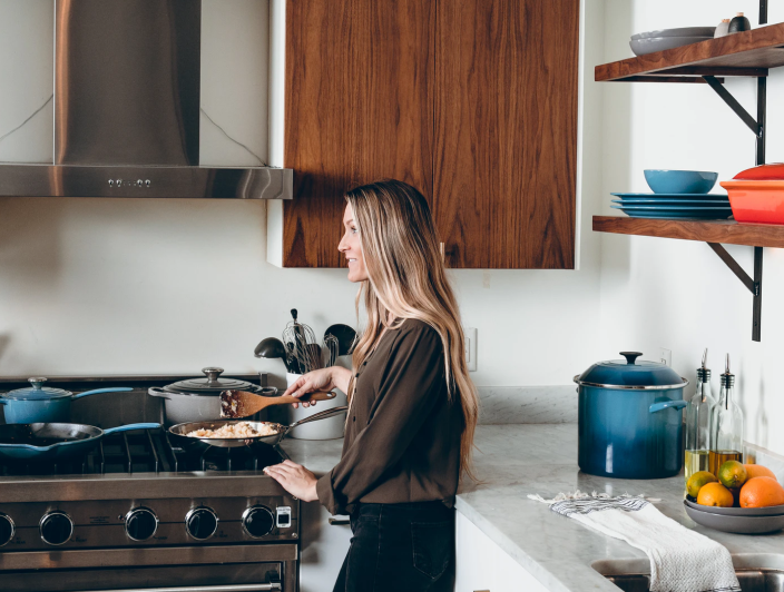 Woman standing at a gas cooktop in a contemporary home kitchen