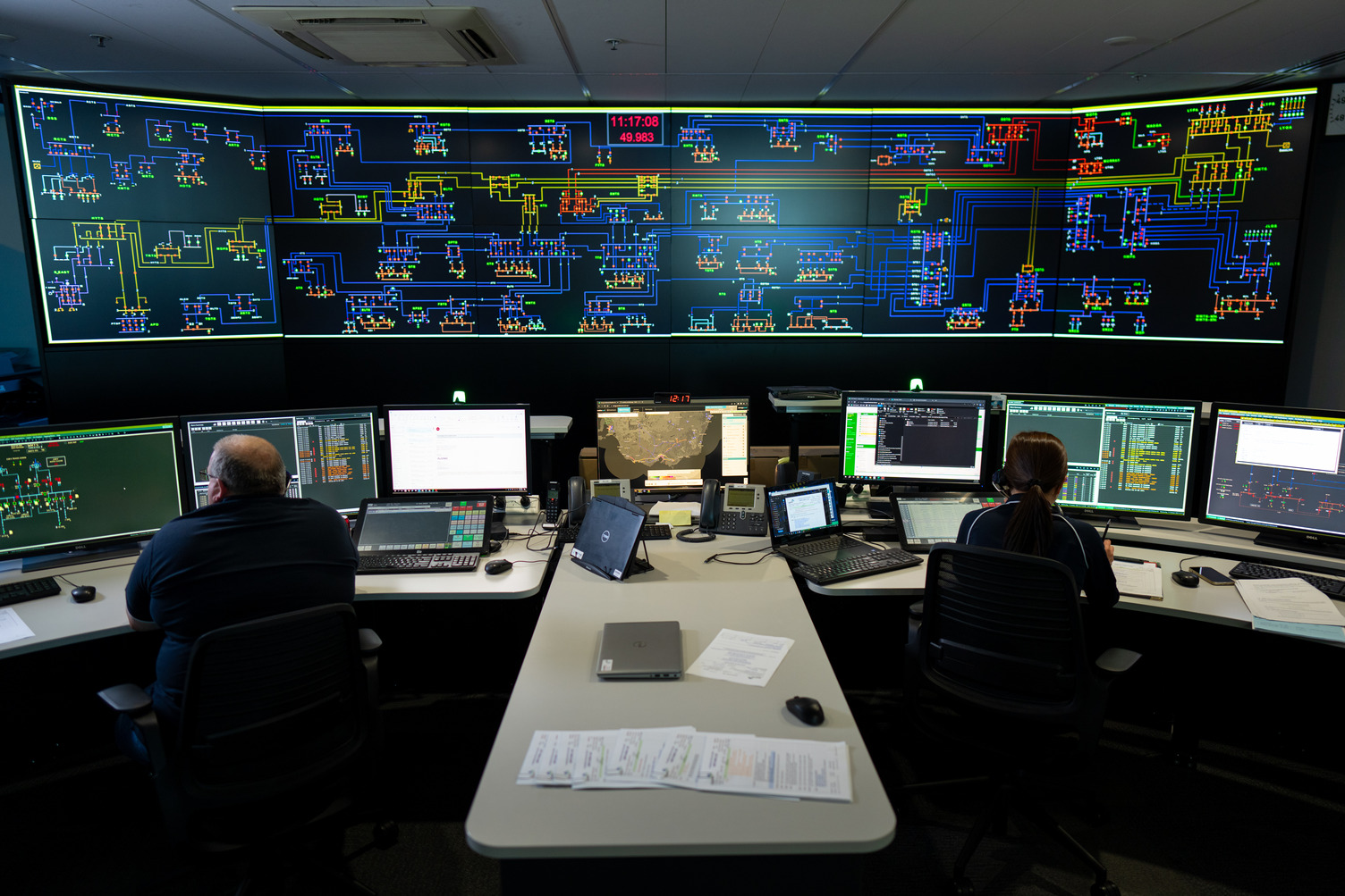 Two people working in an electrical control room