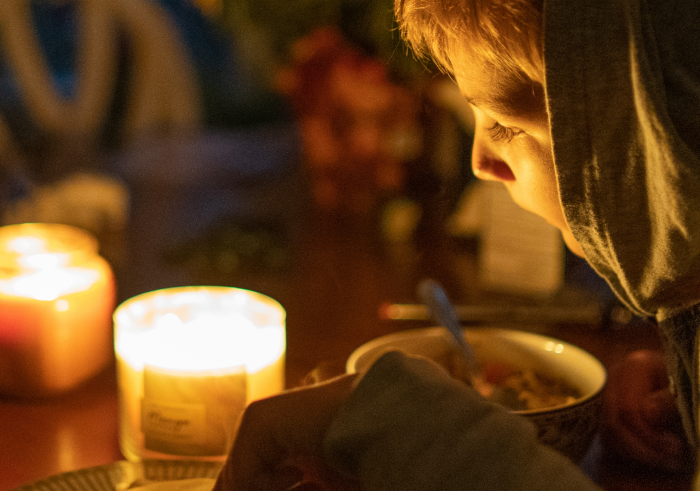 A child indoors looking at two lit candles
