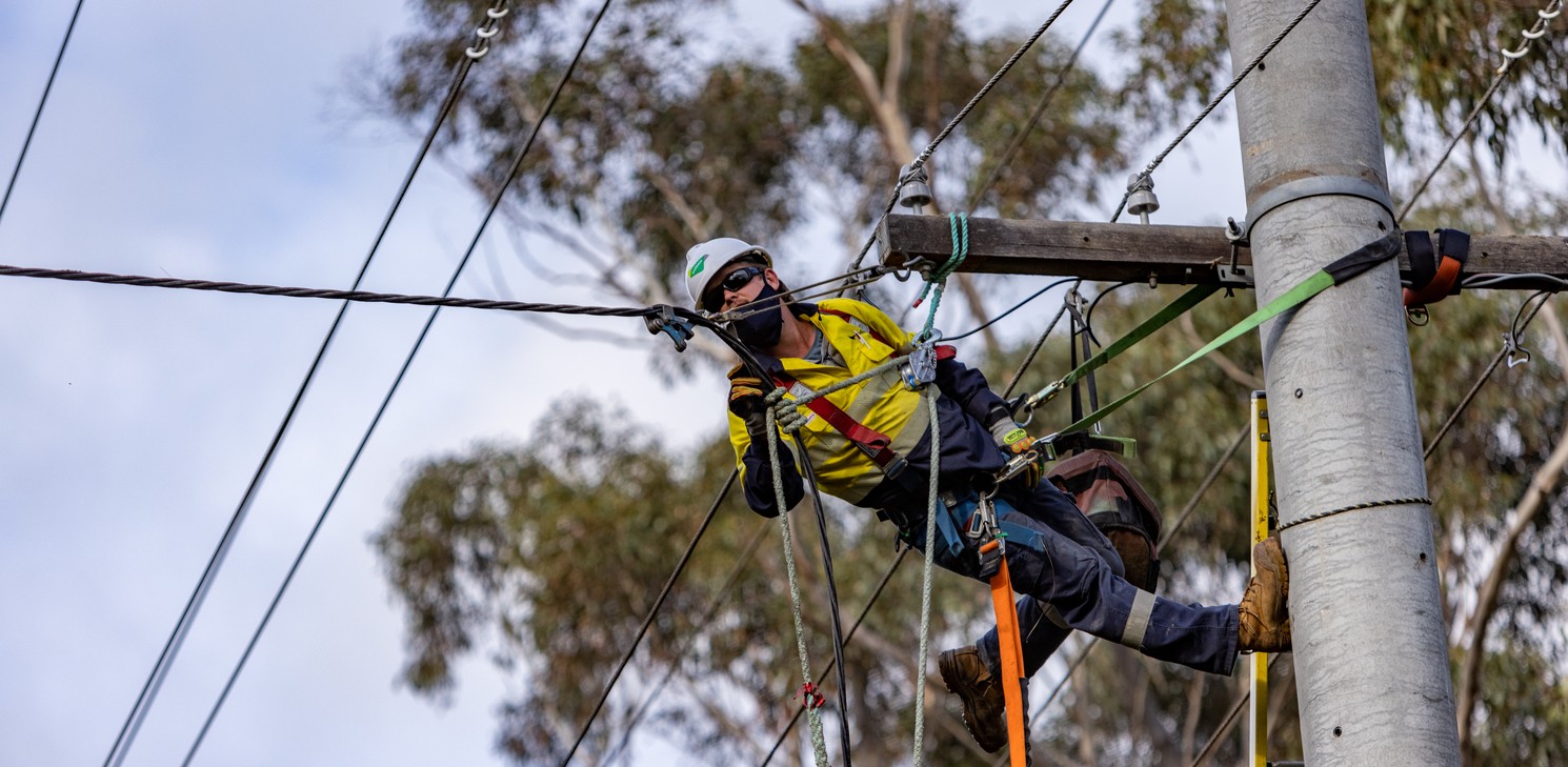 A man repels from a powerline to complete maintenance works