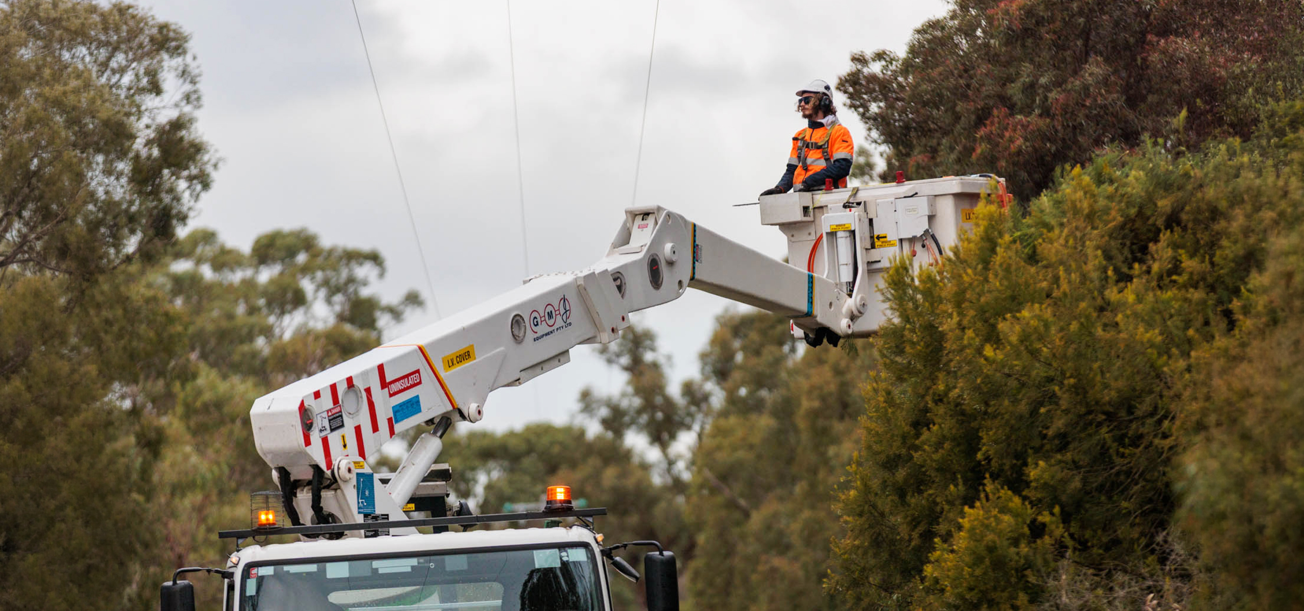 A worker inspecting a transmission line from heavy machinery
