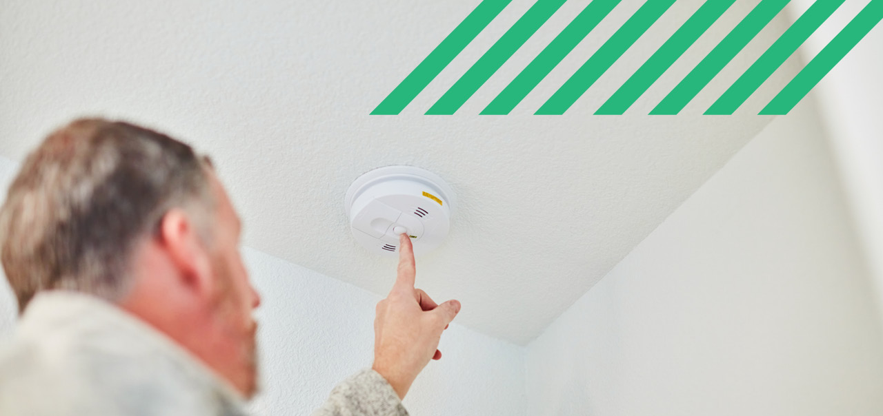 A man pressing a button to turn on a smoke alarm