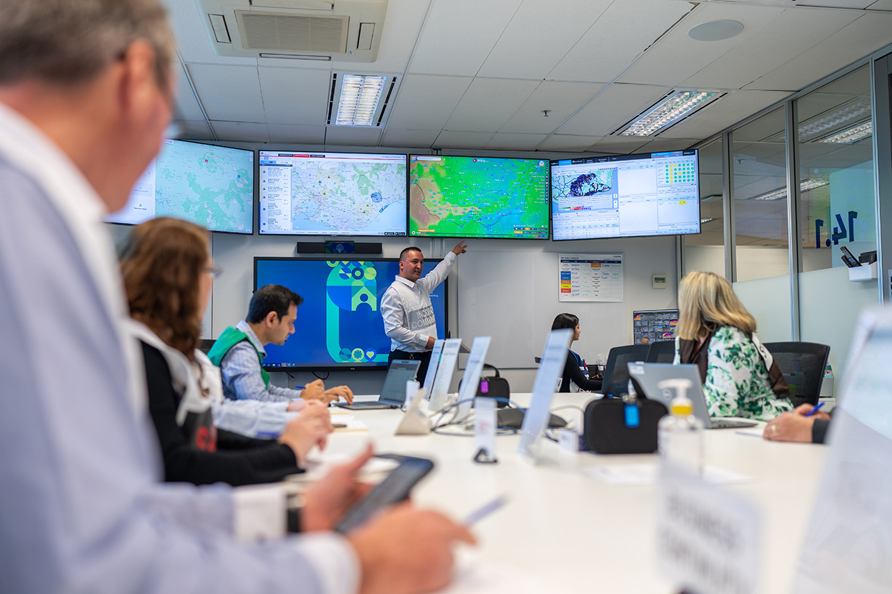 A man presenting with a screen to multiple people inside