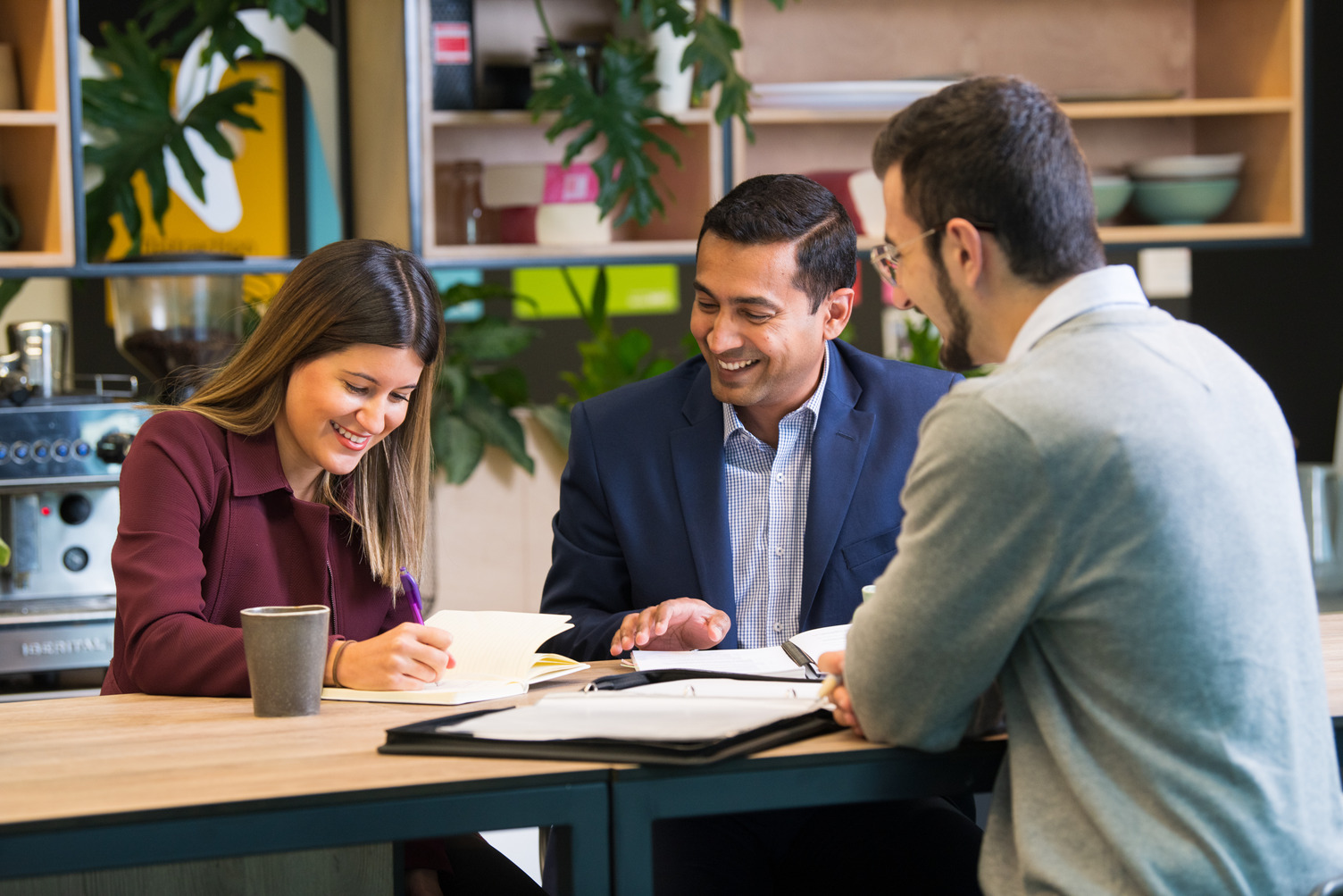 A group of three people smiling at an office desk