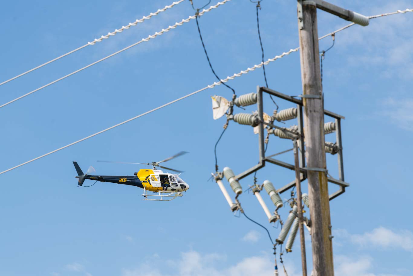 Helicopter flying past a power pole